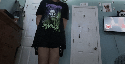 a girl wearing a dracula t-shirt in a bedroom