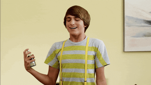 a young man in a striped shirt and suspenders sprays something