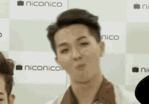 a man is making a funny face while standing in front of a microphone in a room .