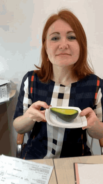 a woman with red hair is holding an avocado on a plate