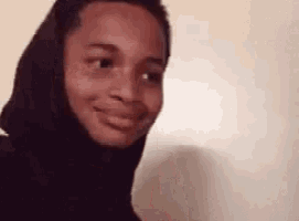 a close up of a person wearing a black hoodie making a funny face .