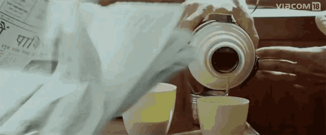 a person pouring liquid into a cup with a newspaper behind them that says viacom 18