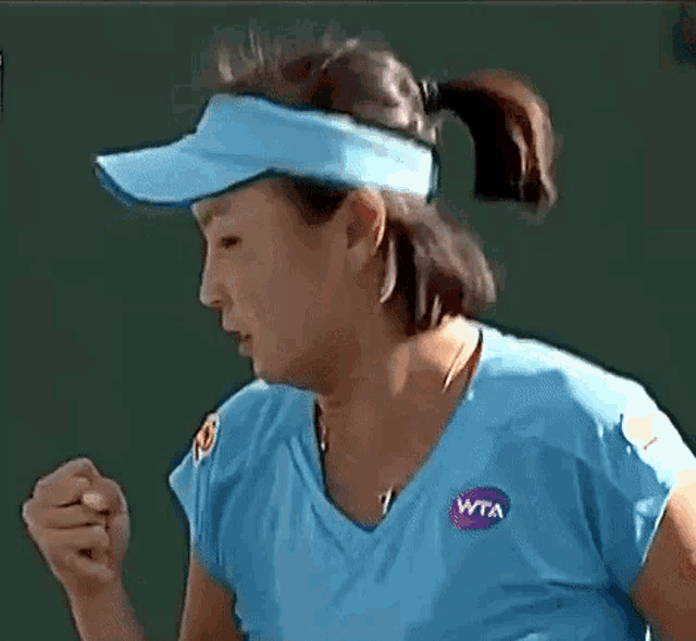 a woman wearing a blue shirt with a wta logo on her chest