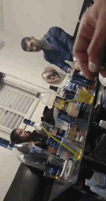 two men are sitting at a table with bottles and cans including one that has the letter u on it