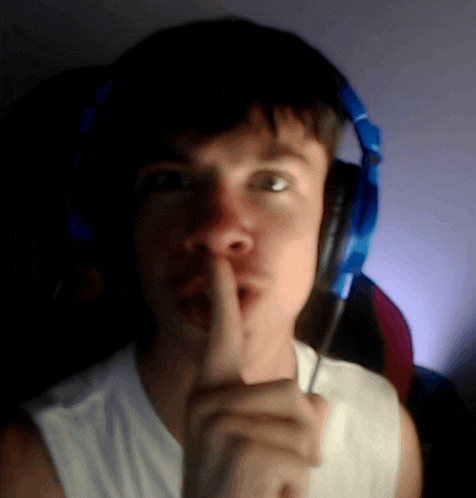 a man wearing headphones is making a shhh gesture