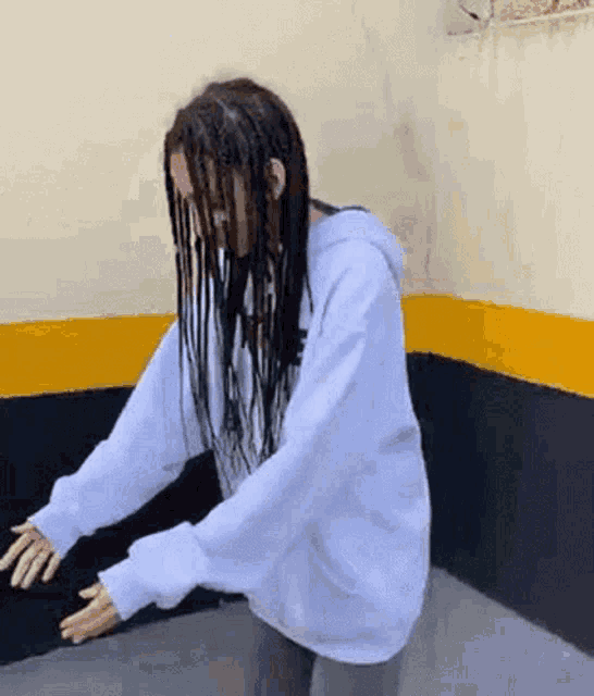 a woman with dreadlocks is dancing in a room with a yellow and black wall .