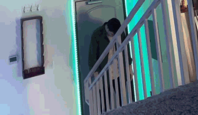 a man is walking down a set of stairs in front of a door that has a green light behind it .