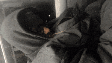 a person in a hooded jacket is sleeping in a blanket