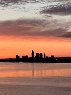 a city skyline silhouetted against a sunset sky over a body of water