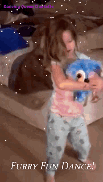a little girl is holding a stuffed animal and dancing with the words furry fun dance on the bottom