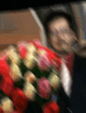 a blurry picture of a man in a suit holding a bouquet of flowers