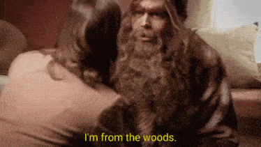 a man with a beard is talking to a woman and says i 'm from the woods