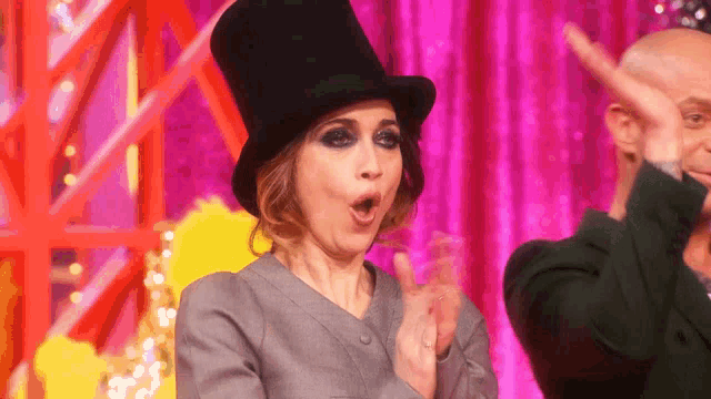 a woman wearing a top hat and a suit is clapping