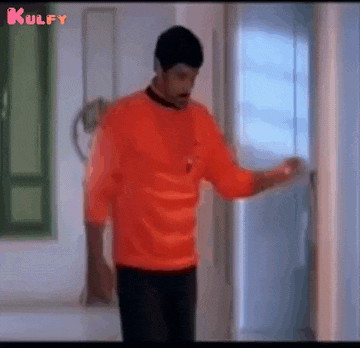 a man in an orange sweater is standing in a hallway .