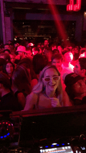 a woman wearing glasses is smiling in front of a crowd of people