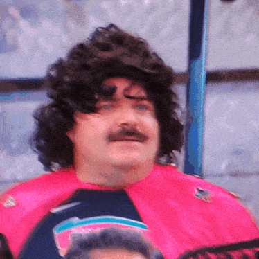 a man with a wig and mustache is wearing a pink shirt that says sharks