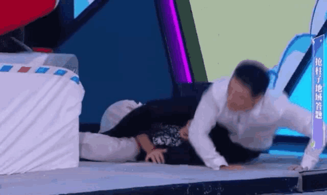 a man is laying on the ground while another man is standing next to him .