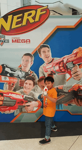 a boy holding a nerf gun in front of a nerf mega poster