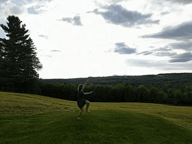 a woman in a blue dress is standing on one leg in a field