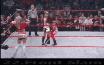 two women are wrestling in a wrestling ring while a referee watches .