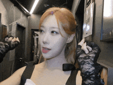 a woman wearing black lace gloves is standing in a hallway with a sign that says glam on it