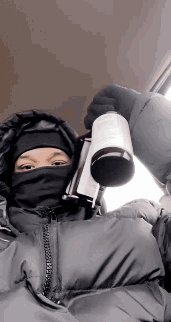 a person wearing a mask and holding a mug