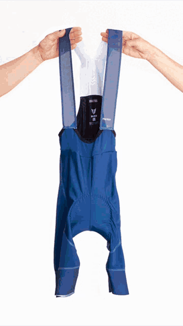 a person is holding a pair of blue bib shorts that say fast on the side