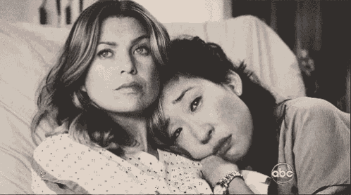 a black and white photo of two women laying on a bed .