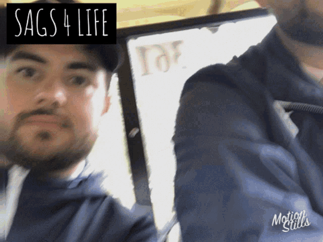 two men are standing next to each other in front of a sign that says " sags 4 life "