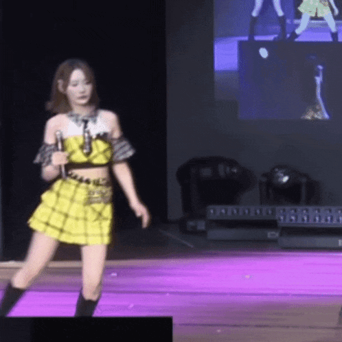 a woman in a yellow dress is dancing on a stage