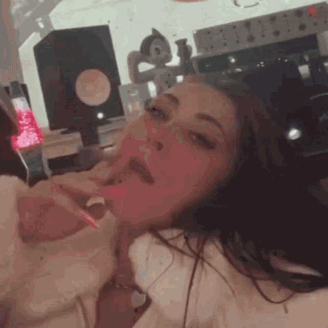 a woman is licking her lips with a pink lollipop while laying on a bed .