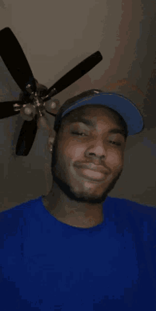 a man wearing a hat and a blue shirt is smiling for the camera