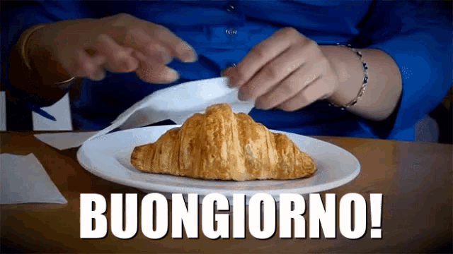a white plate with a croissant on it and the word buongiorno on the bottom