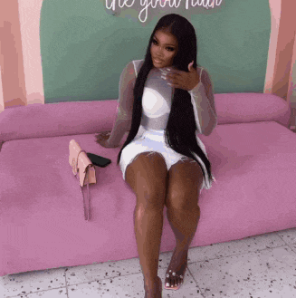 a woman is sitting on a pink couch with a pink purse