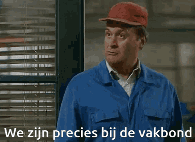 a man wearing a blue jumpsuit and a red hat says we zijn precies bij de vakbond in white letters