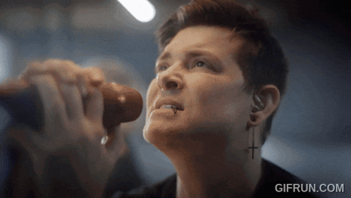 a close up of a person singing into a microphone with gifrun.com in the bottom right corner