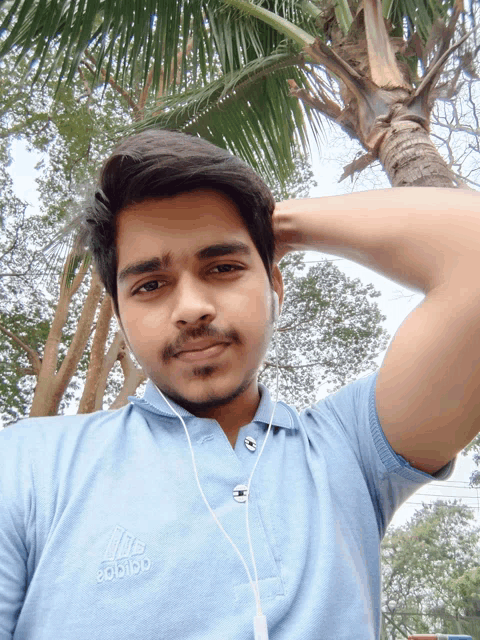 a young man wearing a blue adidas shirt takes a selfie