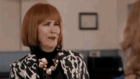 a woman with red hair is wearing a black and white jacket and a necklace .