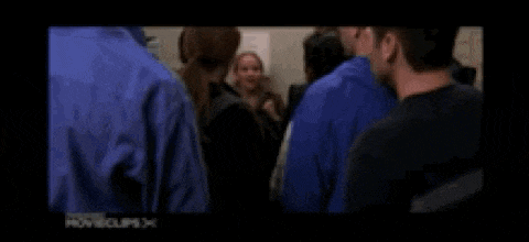 a man and a woman are holding hands in a hallway in a movie .