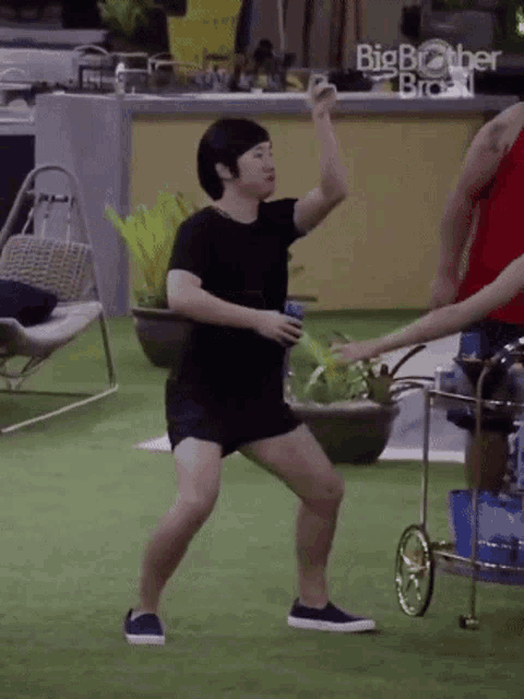a man in shorts is dancing on the grass while holding a beer .
