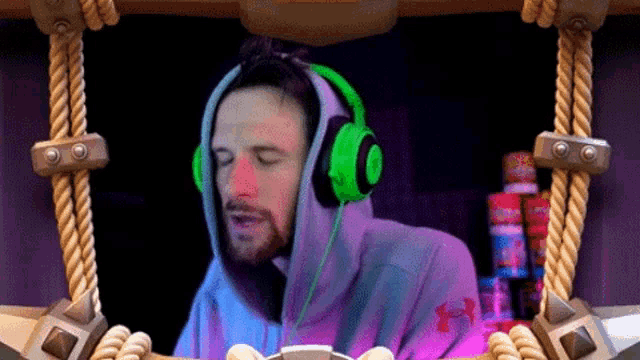 a man wearing headphones and a hoodie is sitting at a desk .