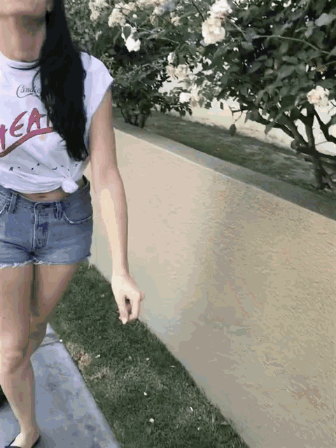 a woman wearing shorts and a t-shirt that says tea is walking down a sidewalk
