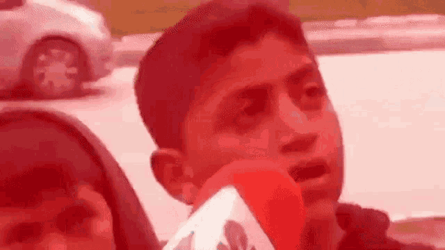 a young boy is talking into a red microphone while standing next to a woman .
