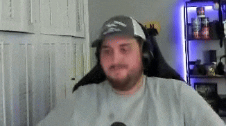 a man with a beard wearing a hat and headphones is sitting in a chair .
