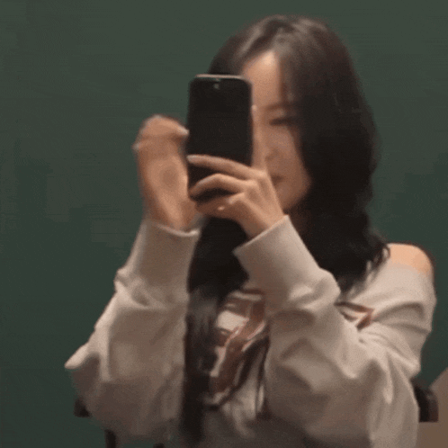a woman is taking a picture of herself with her phone .