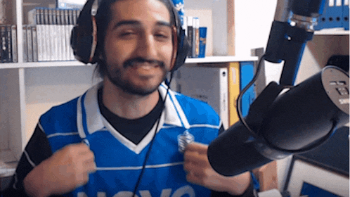 a man wearing headphones stands in front of a microphone and a blue jersey that says nova on it
