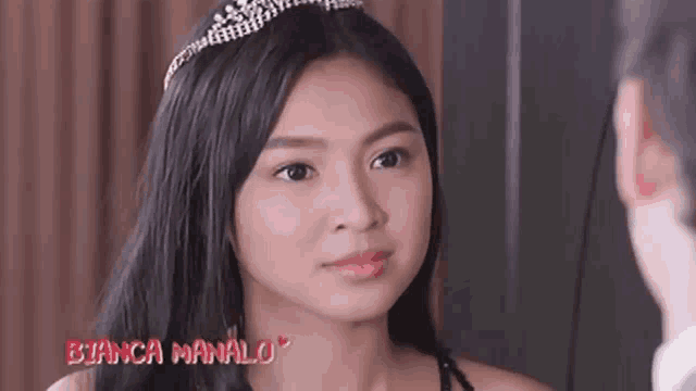 a woman wearing a tiara looks at a man