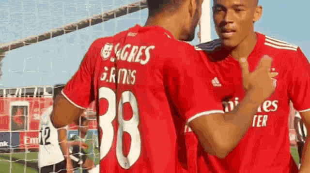 two soccer players wearing red shirts with the number 38 on the back
