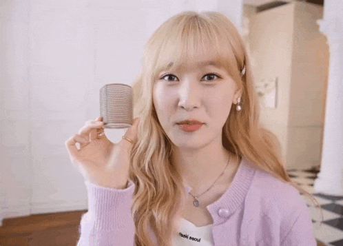 a young woman in a purple sweater is taking a picture of herself in a mirror .