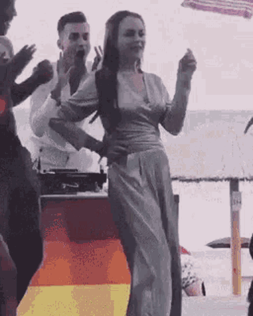 a group of people are dancing on a beach while a man holds a woman 's waist .